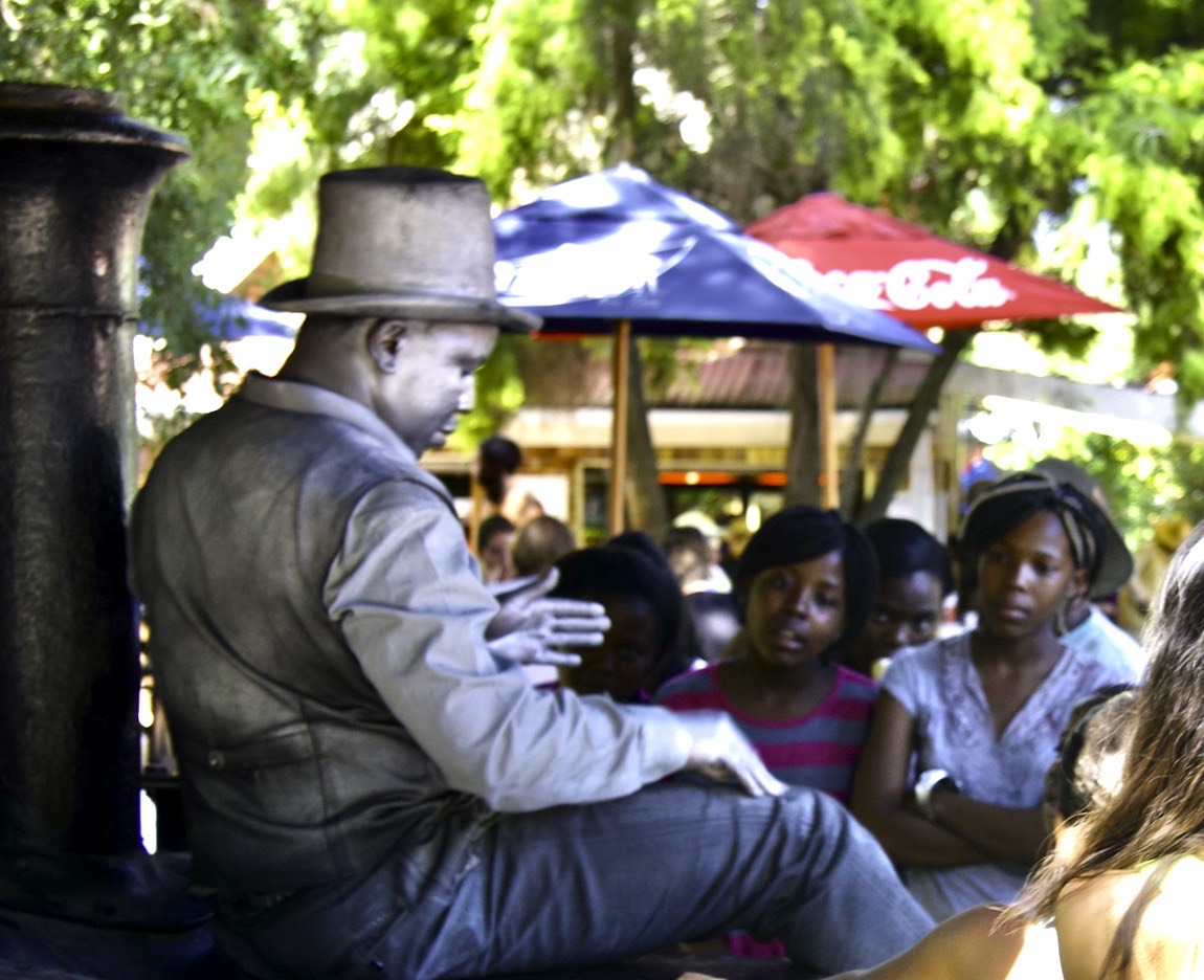 A silvered statue performer with an audience trying to see if he is real